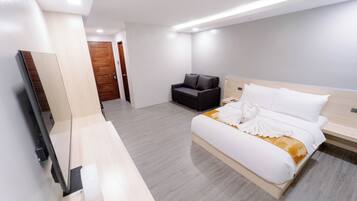 Habitación de hotel moderna con una cama grande, un escritorio con silla, un televisor de pantalla plana y una puerta de madera.