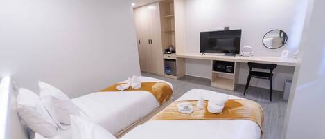 A hotel room with two beds, a desk with a TV, and a wardrobe.