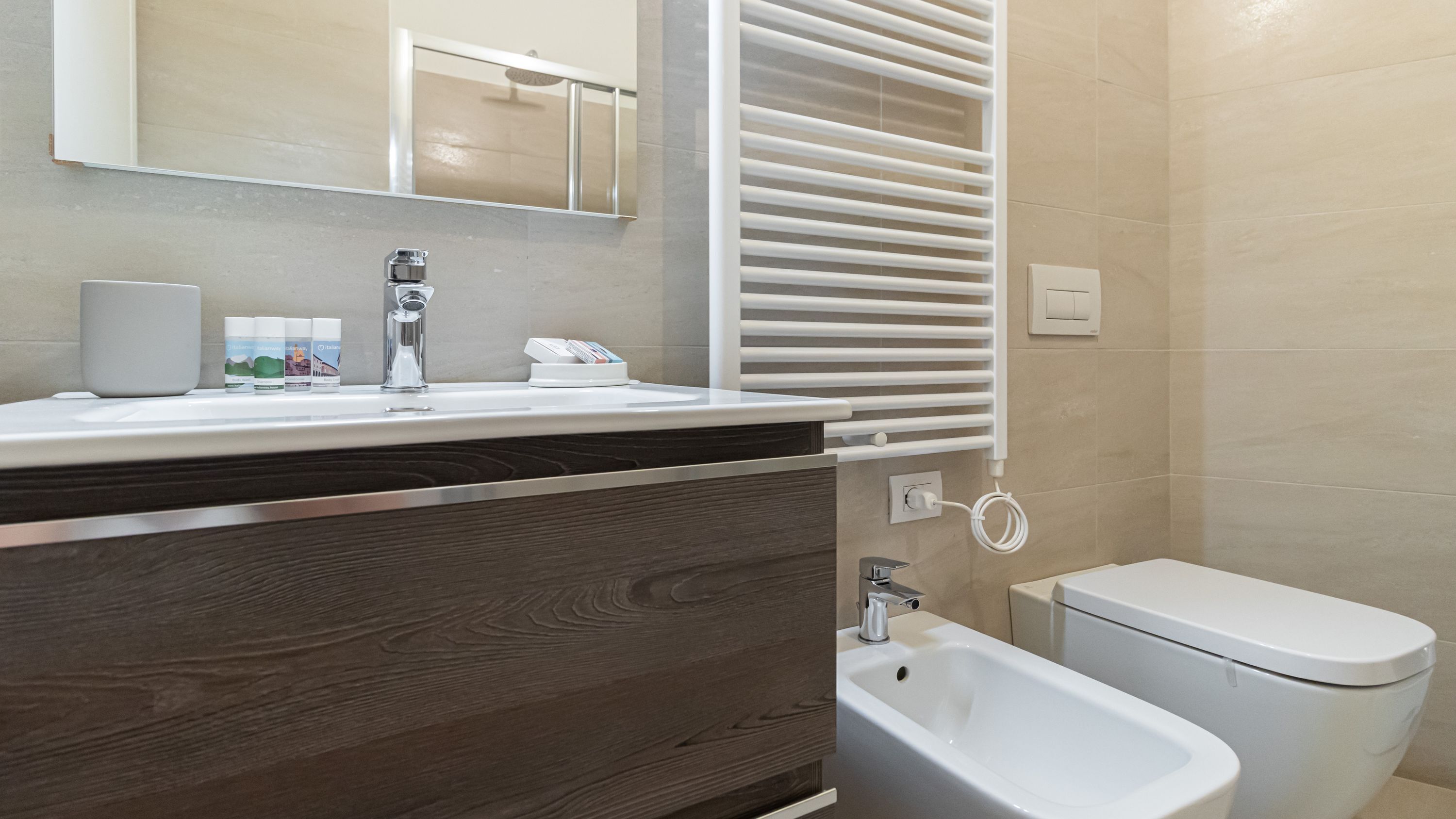 A modern bathroom with a wooden vanity, a bidet, a mirror, and a towel rack.