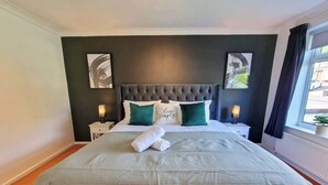 Een hotelkamer met een groot bed, twee nachtkastjes en een raam met gordijnen.