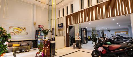 A hotel lobby with a reception desk, seating area, and a row of parked motorcycles.