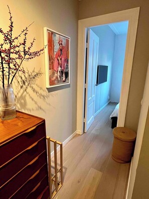 Stylish hallway with a dresser, mirror, and artwork, offering a glimpse into the adjacent room.