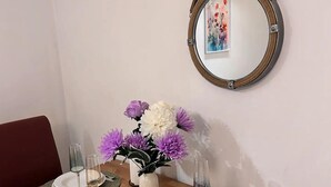 A dining table set with plates, glasses, and a vase of flowers. - Cozy London Apartment - Central Location (London)