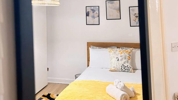 A hotel room with a bed, a hanging light fixture, and three framed pictures on the wall. - Cozy London Apartment - Central Location (London)