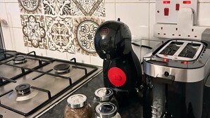 A kitchen with a gas stove, a coffee machine, and decorative tiles. - Cozy London Apartment - Central Location (London)