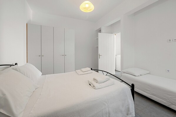 Une chambre moderne avec un grand lit, un lit plus petit et une armoire.