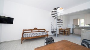 Et moderne interiør med en spiraltrappe, en sofa, et spisebord og et køkken.