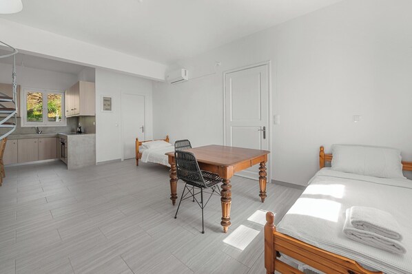 Une chambre avec un lit, une table en bois, une chaise et un petit coin cuisine.