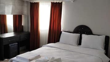 Hotellihuone, jossa on sänky, työpöytä ja tuoli.