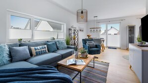 A modern living room with a sofa, coffee table, and dining area. - Beautiful home in Olpenitz with sauna (Olpenitz)