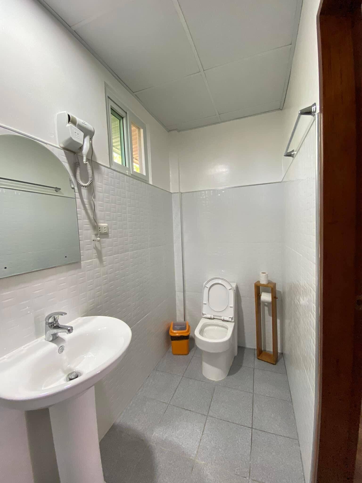 A bathroom with a white sink, a toilet, and a shower area.