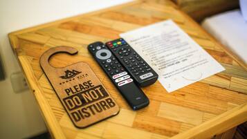 A wooden table with two remote controls and a "Please do not disturb" sign.