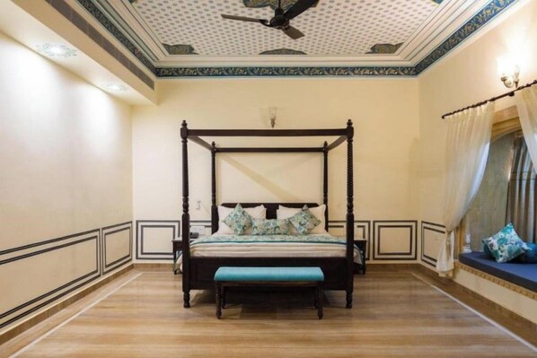 A four-poster bed with a bench in front, a ceiling fan, and a decorative ceiling. - Skk The Fern, Jaisalmer (Jaisalmer)