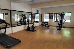Un gimnasio con cinta de correr, elíptica y máquinas de pesas.