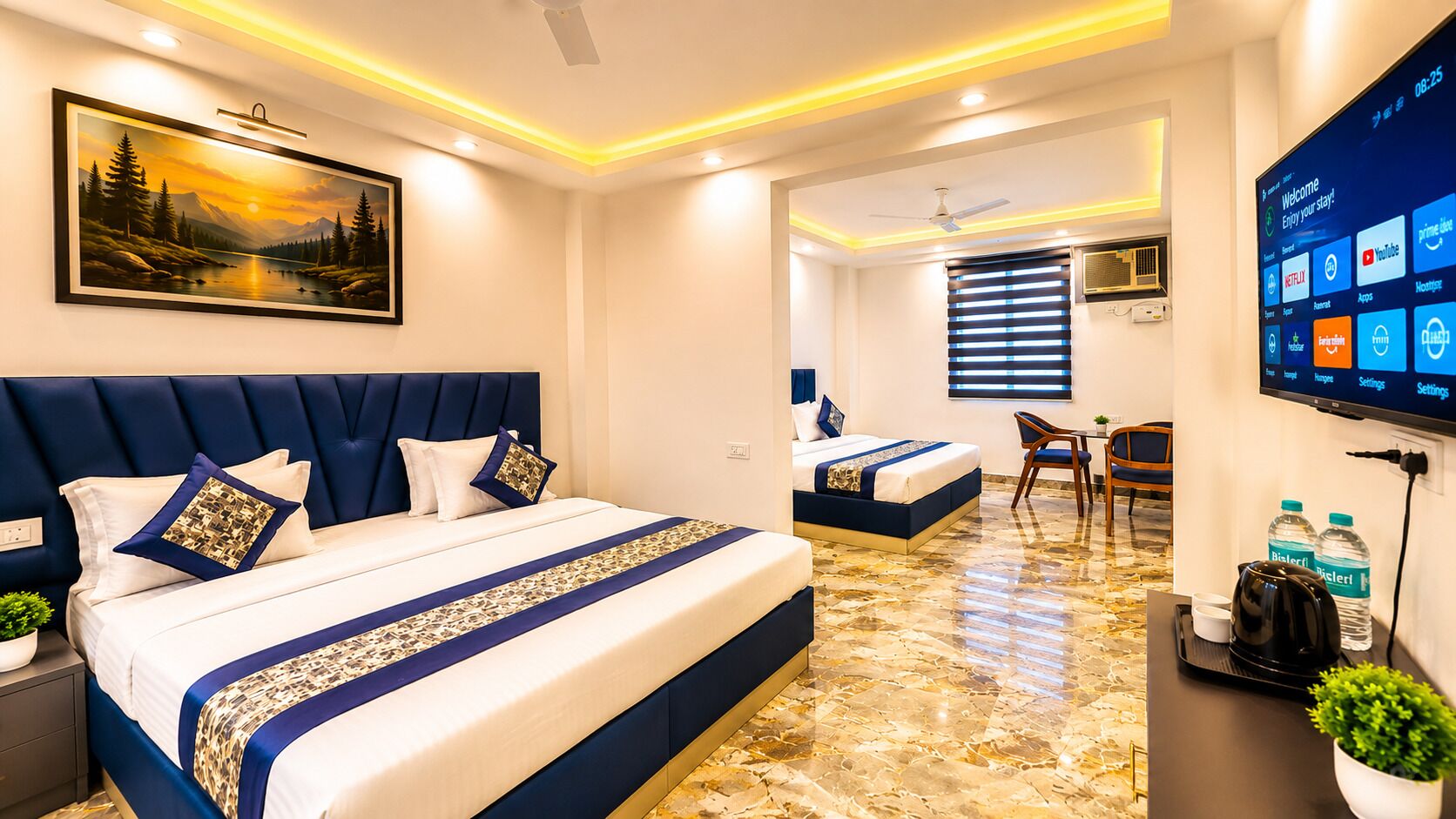 A hotel room with two beds, a TV, a desk with a plant, and a painting on the wall.