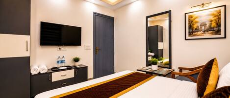 A hotel room with a bed, a desk, a TV, a wardrobe, and a painting on the wall.