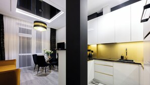 Una cocina moderna con armarios blancos, encimera negra y salpicadero amarillo.