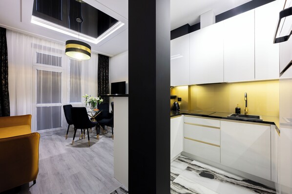 A modern kitchen with white cabinets, a black countertop, and a yellow backsplash. - Native Apartments Słowackiego 14 (Kraków)