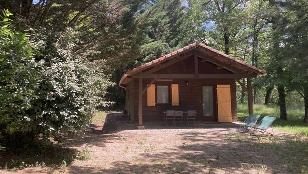 Une cabane en bois avec une véranda, deux chaises et une table.
