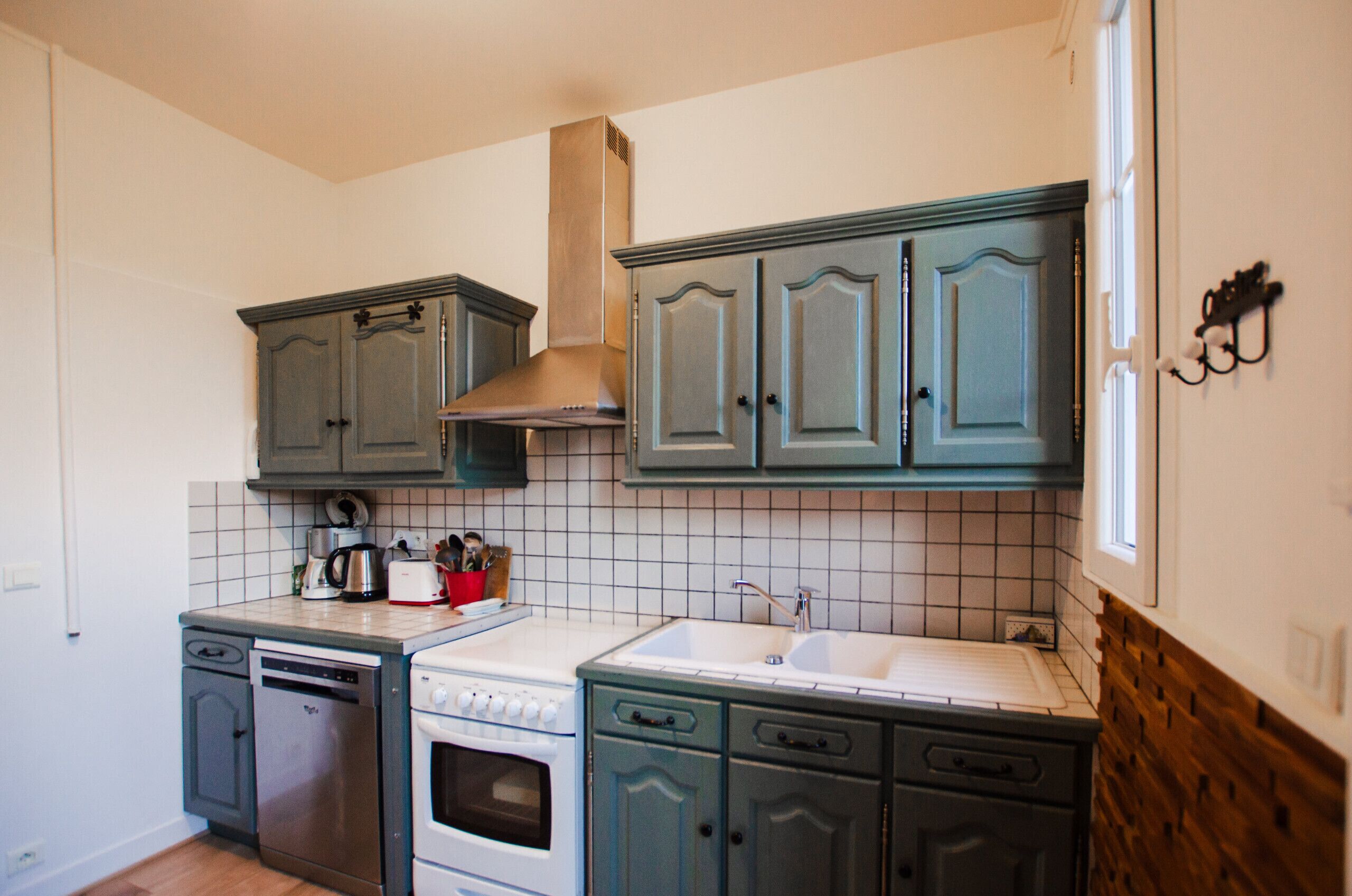 A kitchen with a dishwasher, stove, and sink. There are cabinets and a window.