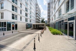 Un edificio moderno de varios pisos, con amplias ventanas y un patio central con bolardos y asientos.
