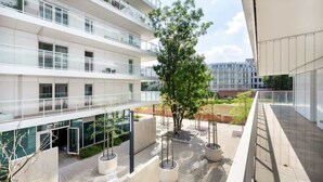 A modern building with multiple floors, large windows, and outdoor seating areas with planters. - Elegant Apartment close to Market Square | Balcony, WiFi (Wrocław)