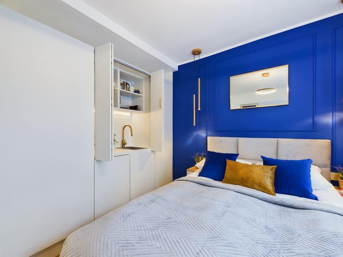 Un dormitorio con cama, mesita de noche, espejo y armario empotrado.