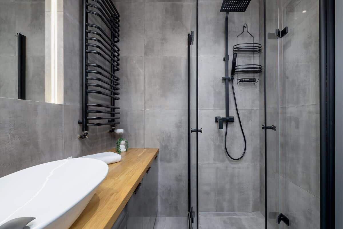 A modern bathroom with a wooden vanity, a glass shower enclosure, and a towel rack.