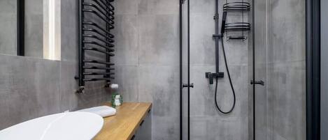A modern bathroom with a wooden vanity, a glass shower enclosure, and a towel rack.
