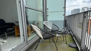 A balcony with two black wire-framed chairs, a small round table, and a sofa. - Royal Docks Luxury 3 Bedroom Apartment (London)