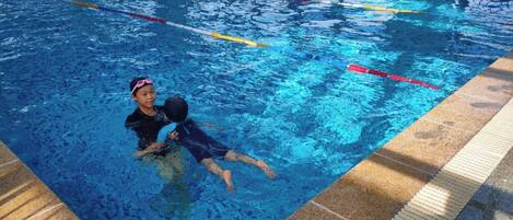 An indoor swimming pool with clear lane dividers and a tiled edge.