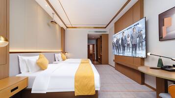 A hotel room with a large bed, bedside tables, a desk, and a TV screen displaying a movie poster.