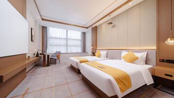 Een hotelkamer met twee bedden, een bureau, een stoel en een groot raam.