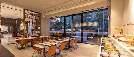 A modern restaurant with a buffet setup, large windows, and a clean, contemporary interior.