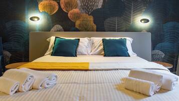 A neatly made bed with striped bedding, two pillows, and rolled towels.