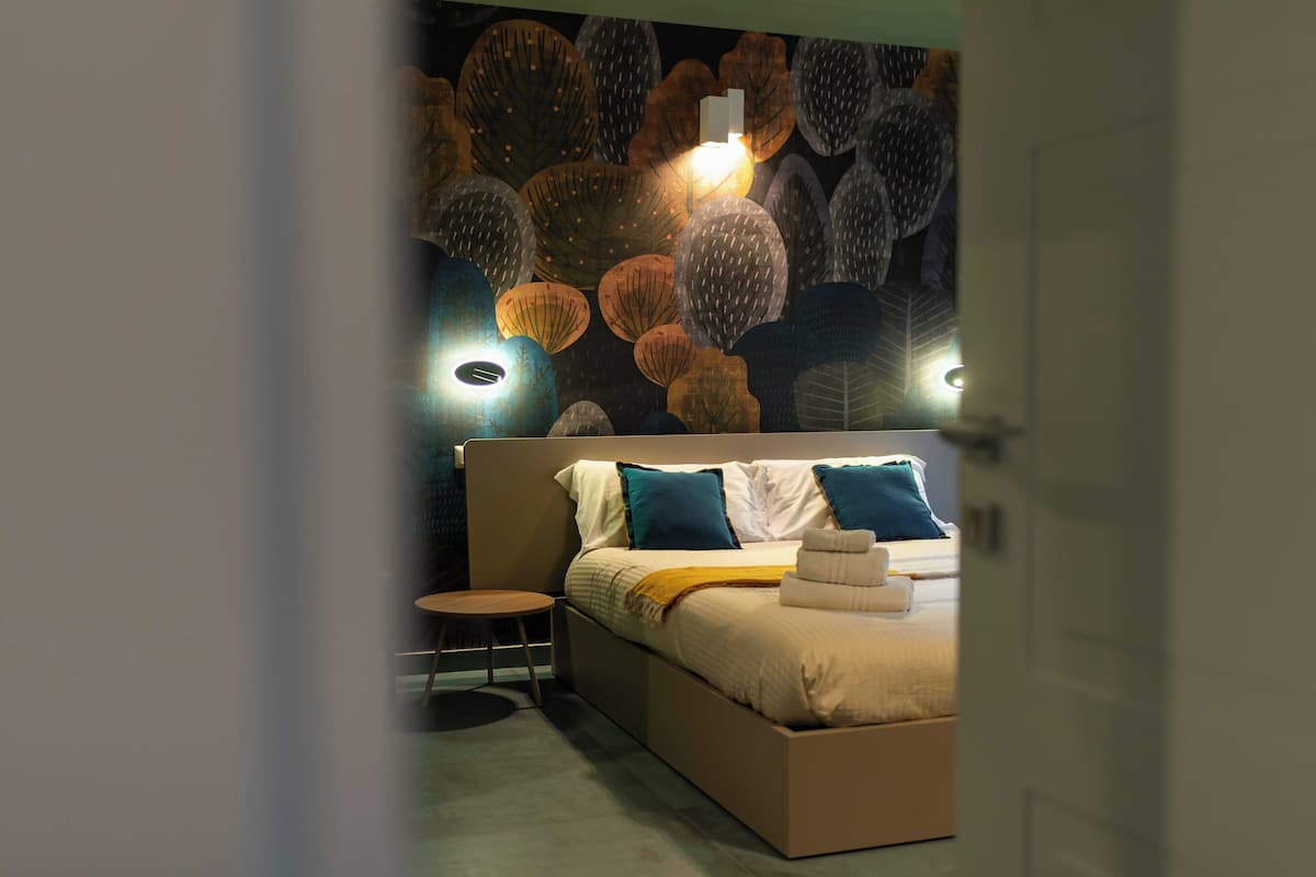 A modern bedroom with a large bed, a round side table, and a wall mural.