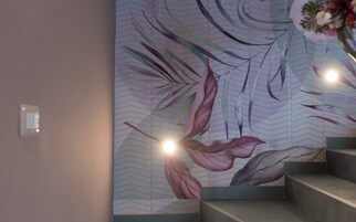 Una scala con un murale decorativo al muro e una piccola lampada.