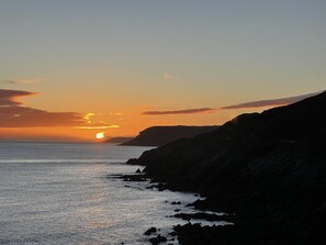 A coastal sunset with rocky cliffs and a calm sea. - Mumbles - House - Seaside - Sleeps11 - Petfriendly (Swansea)
