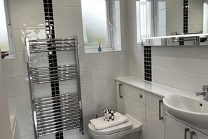 A modern bathroom with a chrome towel rack, a toilet, and a sink. - Mumbles - House - Seaside - Sleeps11 - Petfriendly (Swansea)