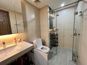 Une salle de bain moderne équipée de toilettes, d’un lavabo et d’une douche à parois de verre.