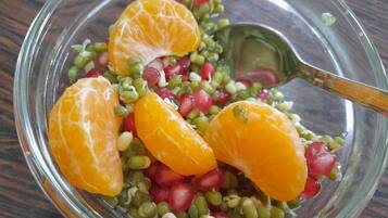 Een schaal fruitsalade met zichtbare ingrediënten zoals granaatappelpitjes en sperziebonen.