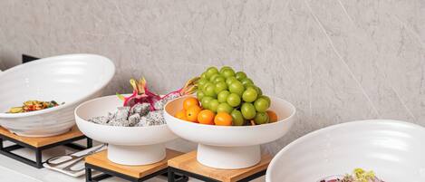 A kitchen counter with three white bowls on wooden stands, each containing different food items.