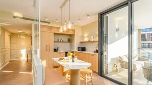 A modern kitchen with a central island, wooden cabinets, and pendant lighting. - Luxury 3BR/2BA Apartment with Terrace in TLV | By SWEETYGUEST (Tel Aviv-Yafo)