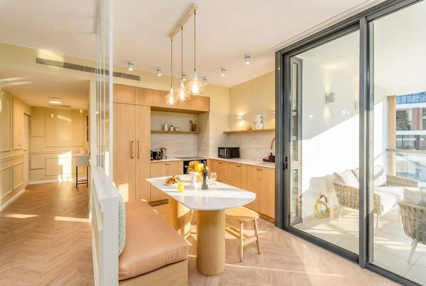 A modern kitchen with a central island, wooden cabinets, and pendant lighting.