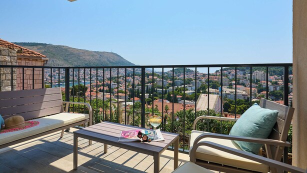 Ein Balkon mit Blick auf eine Stadtansicht, ein Tisch mit einer Zeitschrift und eine Bank.