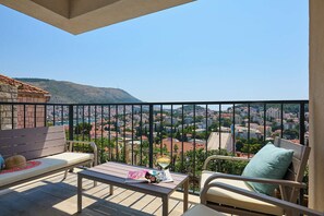 A balcony with a view of a cityscape, a table with a magazine, and a bench. - Hedera Estate, Hedera A48 (Dubrovnik)