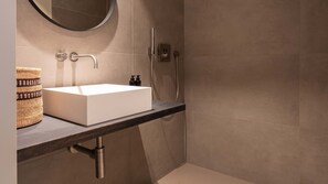 A bathroom with a white sink, a round mirror, and a shower area. - De Gulden Poorte, a LXRYHOME Hotel Collection (Antwerp)