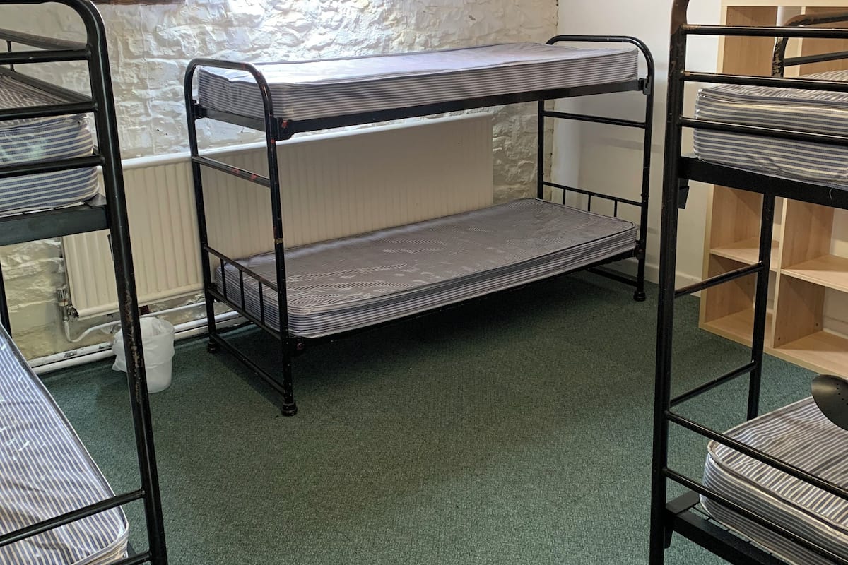 A dormitory room with bunk beds, a radiator, a skylight, and a wooden chair.