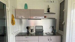 Une cuisine compacte équipée d’une cuisinière intégrée, d’une machine à café et d’un évier.