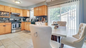A modern kitchen with wooden cabinets, a stainless steel oven, and a dining area with white upholstered chairs. - Westland Family Home w/ Deck & Fenced Yard (Westland)